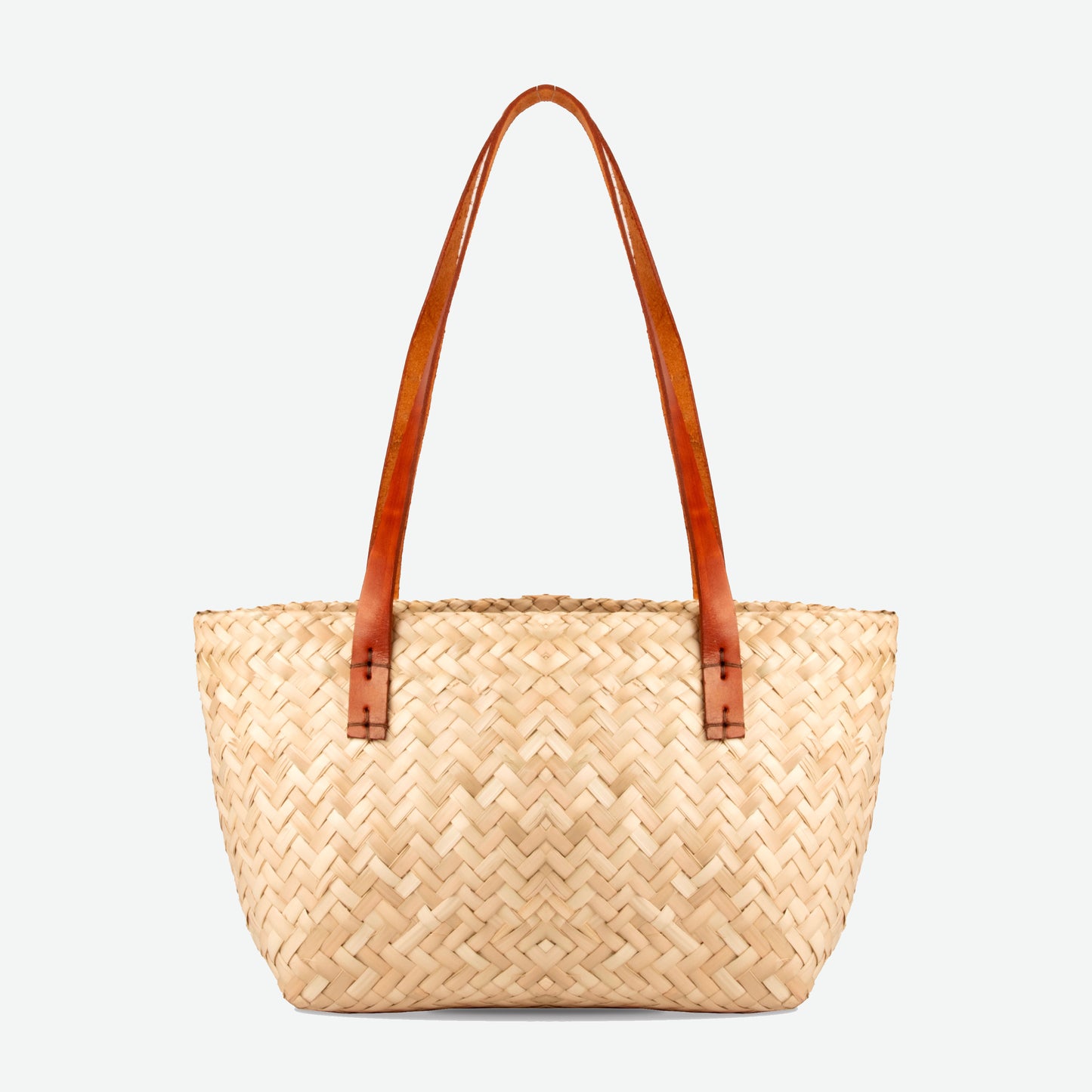Woven straw tote bag with brown leather handles on a light gray background