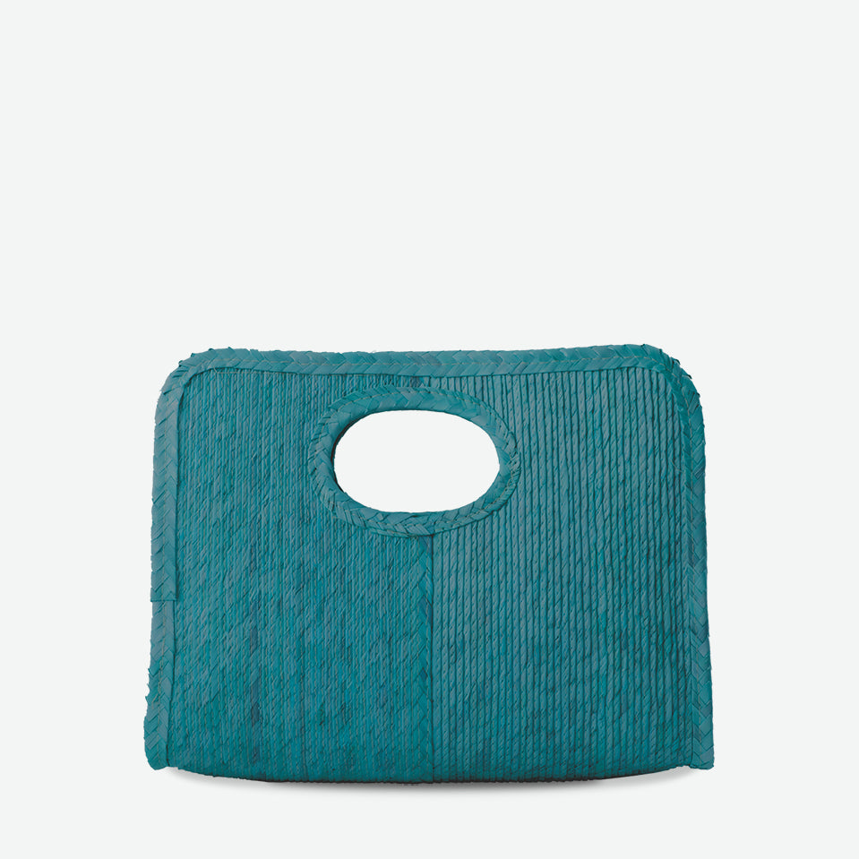 Mini square handheld straw tote in teal, woven from palm and dyed with organic colors. Summer-ready design by Per Lei New York.