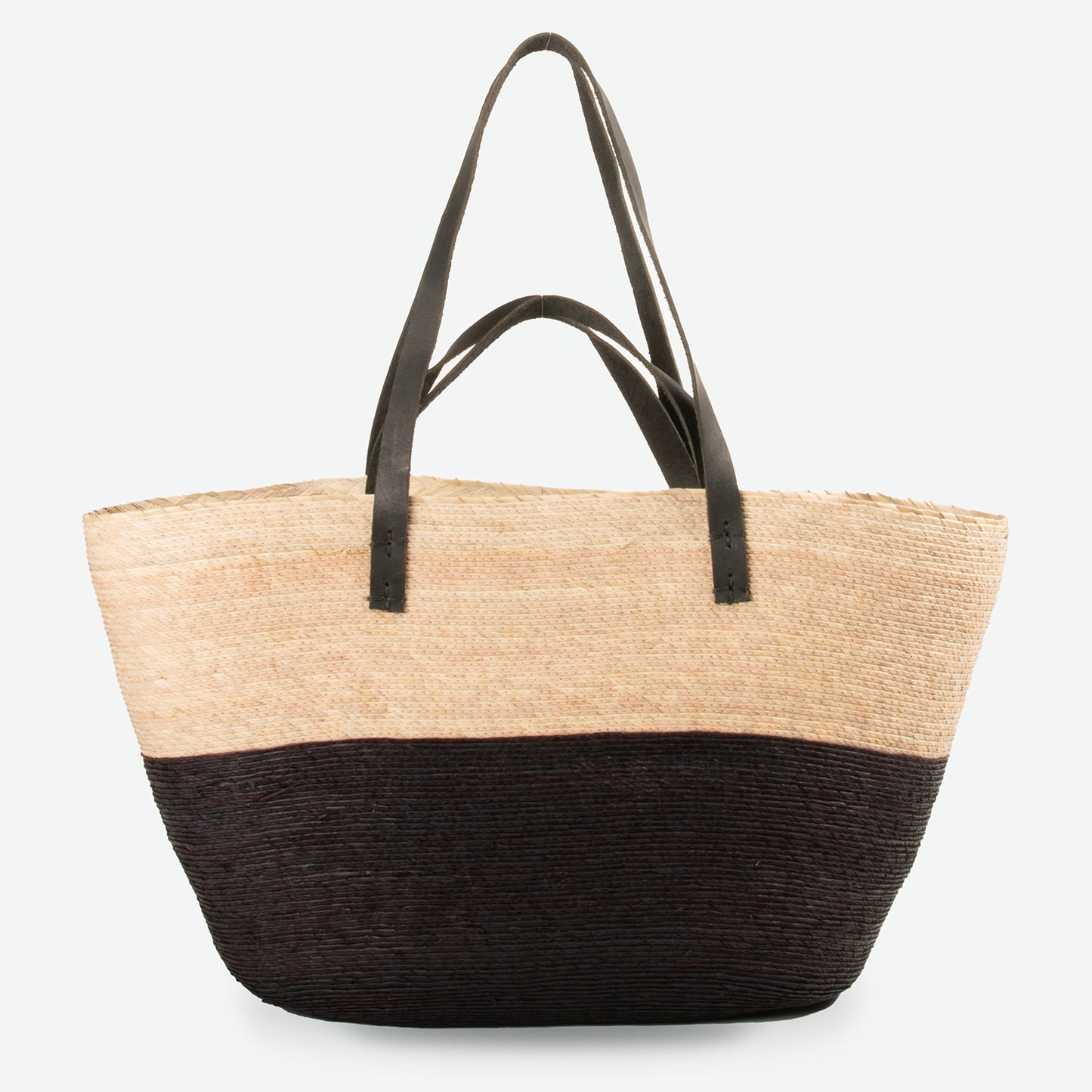 Large black and natural straw market tote with black leather straps, handwoven and standing upright.