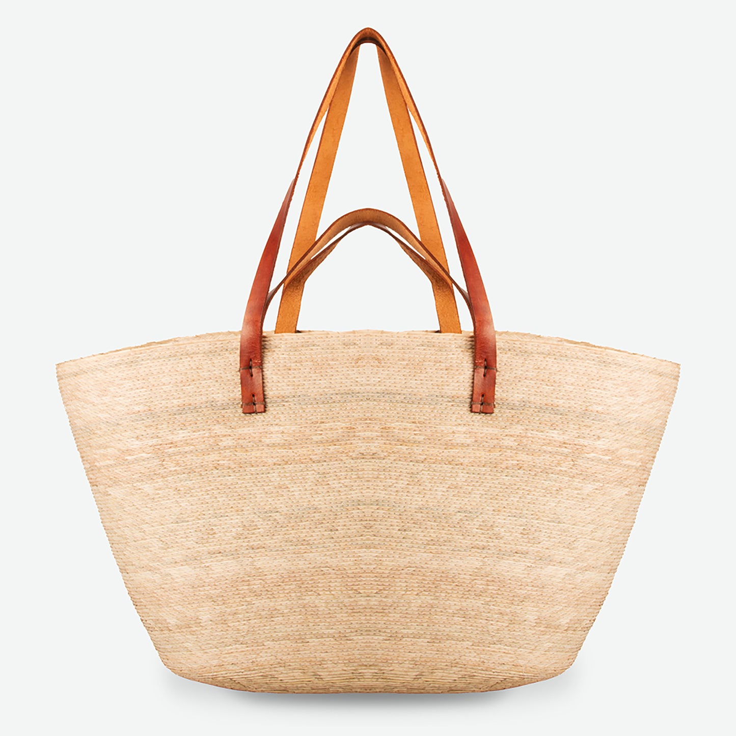 Natural straw beach tote with brown leather straps, handwoven and standing upright