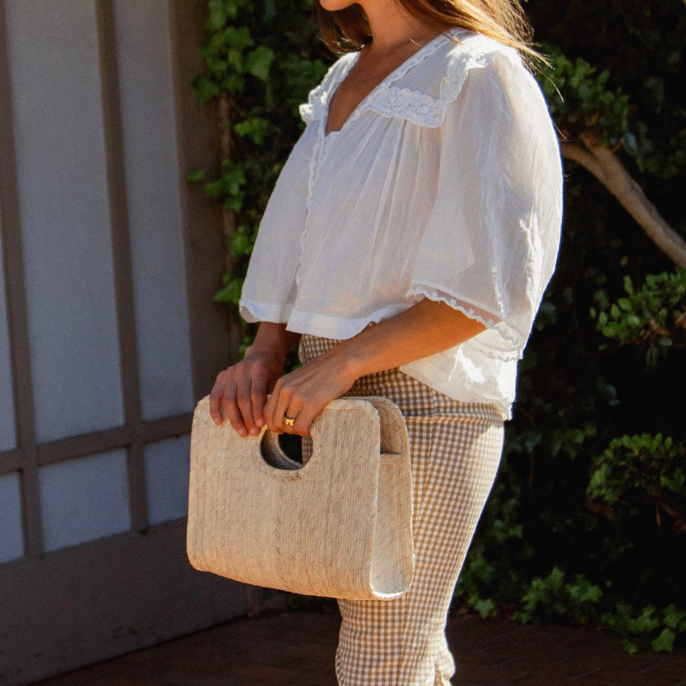 Woman holding Natural color Square Straw Beach Tote by Per Lei New York.